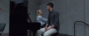 Movie still from “Tár” (2022), directed by Todd Field – A man and a woman sitting next to a piano; Medium shot, Over the shoulder angle