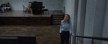 Movie still from “Tár” (2022), directed by Todd Field – A woman standing in front of a piano in a room; Wide shot, High angle