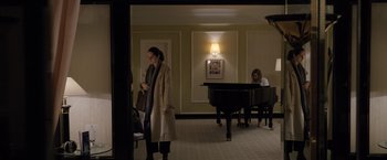 Movie still from “Tár” (2022), directed by Todd Field – A woman standing in front of a piano in a living room; Wide shot, High angle
