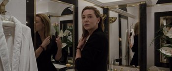 Movie still from “Tár” (2022), directed by Todd Field – A woman standing in front of a mirror in a room; Medium shot, Over the shoulder angle