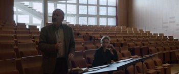 Movie still from “Tár” (2022), directed by Todd Field – A man and a woman sitting at a table in a lecture hall; Medium shot, Over the shoulder angle