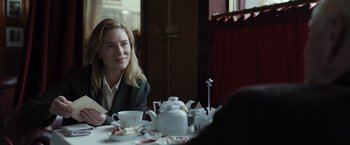 Movie still from “Tár” (2022), directed by Todd Field – A woman sitting at a table with a tea pot; Medium shot, Over the shoulder angle