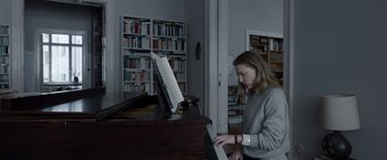 Movie still from “Tár” (2022), directed by Todd Field – A woman is playing the piano in a library; Medium shot, Low angle