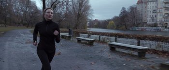 Movie still from “Tár” (2022), directed by Todd Field – A woman is running in a park near benches; Medium shot, Over the shoulder angle