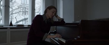 Movie still from “Tár” (2022), directed by Todd Field – A woman sitting in front of a black piano; Medium shot, High angle