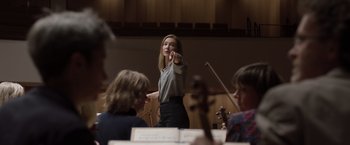 Movie still from “Tár” (2022), directed by Todd Field – A woman directing a group of people in a room; Medium shot, Low angle
