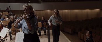 Movie still from “Tár” (2022), directed by Todd Field – A group of people in a room playing instruments; Medium shot, Low angle