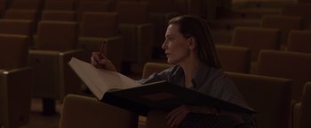 Movie still from “Tár” (2022), directed by Todd Field – A woman sitting in a chair writing on a piece of paper; Medium shot, High angle