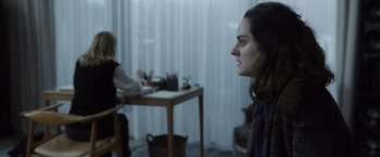 Movie still from “Tár” (2022), directed by Todd Field – A woman sitting in front of a table with a person sitting at a desk in front of her; Medium shot, Over the shoulder angle