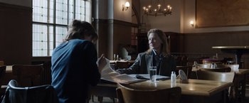 Movie still from “Tár” (2022), directed by Todd Field – Two people sitting at a table in front of papers; Medium shot, Over the shoulder angle
