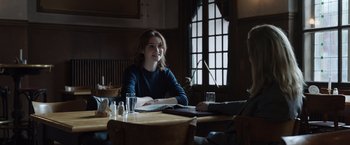 Movie still from “Tár” (2022), directed by Todd Field – A woman sitting at a table in a restaurant; Medium shot, Over the shoulder angle