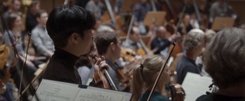 Movie still from “Tár” (2022), directed by Todd Field – A group of people that are sitting in a room with musical instruments; Close Up shot, Low angle