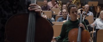 Movie still from “Tár” (2022), directed by Todd Field – A woman holding a cello in front of a group of people; Medium shot, Low angle
