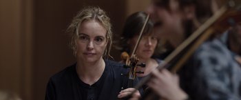 Movie still from “Tár” (2022), directed by Todd Field – A woman is holding a violin while another woman is holding a violin; Close Up shot, Over the shoulder angle