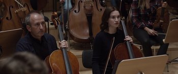 Movie still from “Tár” (2022), directed by Todd Field – A woman holding a cello while sitting next to another person; Medium shot, Over the shoulder angle