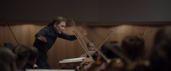 Movie still from “Tár” (2022), directed by Todd Field – A conductor directing a band in front of a group of people; Medium shot, Low angle
