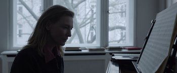 Movie still from “Tár” (2022), directed by Todd Field – A woman sitting in front of a piano in a room; Close Up shot, Over the shoulder angle