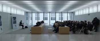 Movie still from “Tár” (2022), directed by Todd Field – A group of people sitting in a room with windows on either side of them; Wide shot, High angle