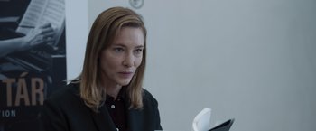 Movie still from “Tár” (2022), directed by Todd Field – A woman in a black jacket is looking at the camera; Close Up shot, Over the shoulder angle