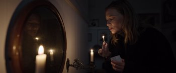 Movie still from “Tár” (2022), directed by Todd Field – A woman lighting a candle in front of a mirror; Medium shot, Low angle