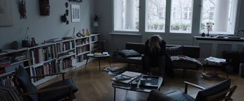 Movie still from “Tár” (2022), directed by Todd Field – A person sitting on a couch in a living room; Medium shot, High angle