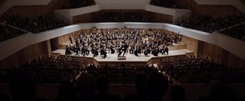 Movie still from “Tár” (2022), directed by Todd Field – An orchestra is performing in a large auditorium; Extreme Wide shot, Low angle