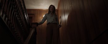 Movie still from “Tár” (2022), directed by Todd Field – A woman standing on a staircase holding a knife; Medium shot, Low angle