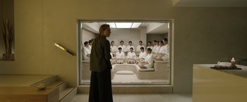 Movie still from “Tár” (2022), directed by Todd Field – A group of people sitting in a room with a man standing in front of them; Wide shot, High angle