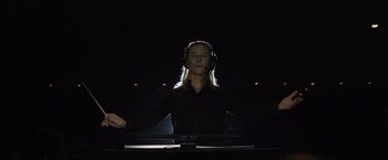 Movie still from “Tár” (2022), directed by Todd Field – A woman wearing a black shirt and a headset; Medium shot, Low angle