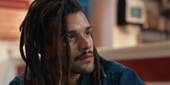 A person with dreads looking to his left