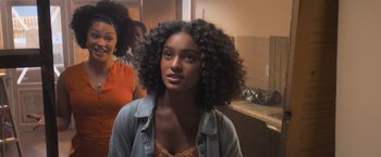 A young woman with long curly black hair in front of a mirror