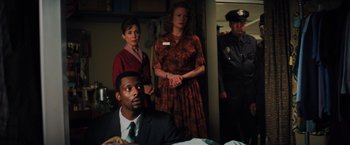 Movie still from “Unbreakable” (2000), directed by M. Night Shyamalan – A group of people standing in a living room; Medium shot, High angle