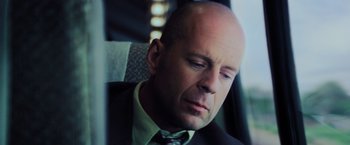 Movie still from “Unbreakable” (2000), directed by M. Night Shyamalan – A man in a suit and tie sitting in a car; Close Up shot, Low angle