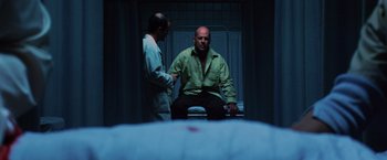 Movie still from “Unbreakable” (2000), directed by M. Night Shyamalan – Two men are talking in a room with a bed in front of them; Medium shot, Low angle