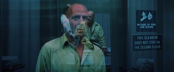 Movie still from “Unbreakable” (2000), directed by M. Night Shyamalan – A man with a bald head is talking on the phone; Close Up shot, Low angle