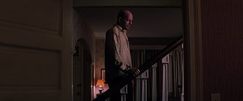 Movie still from “Unbreakable” (2000), directed by M. Night Shyamalan – A man standing at the top of a stair railing; Medium shot, Low angle