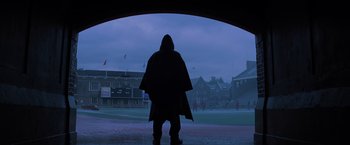 Movie still from “Unbreakable” (2000), directed by M. Night Shyamalan – A person in a hooded jacket standing under an arch; Extreme Wide shot, Low angle