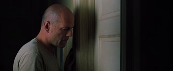 Movie still from “Unbreakable” (2000), directed by M. Night Shyamalan – A bald man standing in front of a white door; Close Up shot, Over the shoulder angle