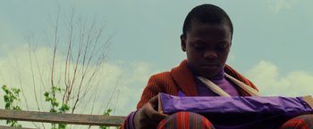 Movie still from “Unbreakable” (2000), directed by M. Night Shyamalan – A young boy sitting on top of a wooden bench; Close Up shot, Low angle