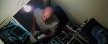 Movie still from “Unbreakable” (2000), directed by M. Night Shyamalan – A bald headed man is looking at a laptop; Medium shot, Overhead angle