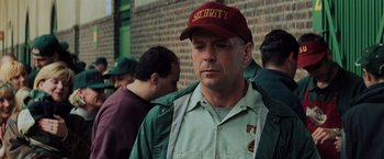 Movie still from “Unbreakable” (2000), directed by M. Night Shyamalan – A man wearing a security hat standing in front of a brick wall; Close Up shot, Over the shoulder angle