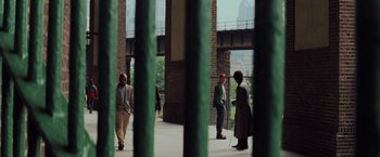 Movie still from “Unbreakable” (2000), directed by M. Night Shyamalan – A group of people standing in front of a brick building; Extreme Wide shot, High angle