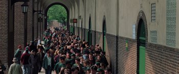 Movie still from “Unbreakable” (2000), directed by M. Night Shyamalan – A large group of people standing in a line outside; Extreme Wide shot, High angle