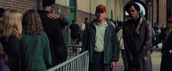 Movie still from “Unbreakable” (2000), directed by M. Night Shyamalan – A man in a green jacket and a red hat; Medium shot, Over the shoulder angle