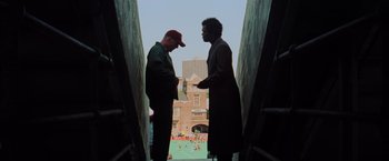 Movie still from “Unbreakable” (2000), directed by M. Night Shyamalan – Two men standing next to each other on a bridge; Wide shot, Low angle