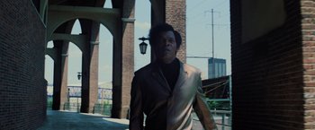 Movie still from “Unbreakable” (2000), directed by M. Night Shyamalan – A man in a suit walking down a street; Medium shot, Low angle