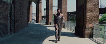 Movie still from “Unbreakable” (2000), directed by M. Night Shyamalan – A man in a long coat walking down a sidewalk; Wide shot, Low angle