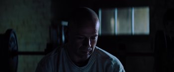 Movie still from “Unbreakable” (2000), directed by M. Night Shyamalan – A man with bald head looking down at his face; Close Up shot, Low angle