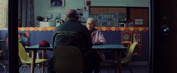 Movie still from “Unbreakable” (2000), directed by M. Night Shyamalan – Two people sitting at a table talking to each other; Medium shot, Over the shoulder angle