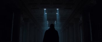 Movie still from “Unbreakable” (2000), directed by M. Night Shyamalan – A person standing in a dark room under lights; Wide shot, Low angle